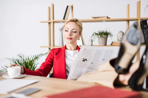 Portrait of businesswoman with newspaper at workplace — Stock Photo