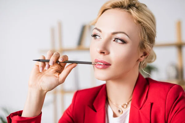 Porträt einer nachdenklichen Geschäftsfrau mit Bleistift in der Hand, die im Büro wegschaut — Stockfoto