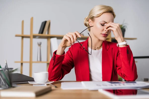 Porträt einer überlasteten Geschäftsfrau, die am Arbeitsplatz im Büro sitzt — Stockfoto