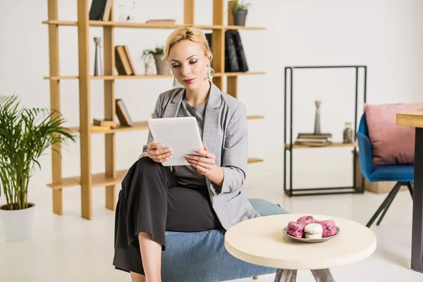 Schöne Geschäftsfrau mit Tablet auf Stuhl im Büro — Stockfoto