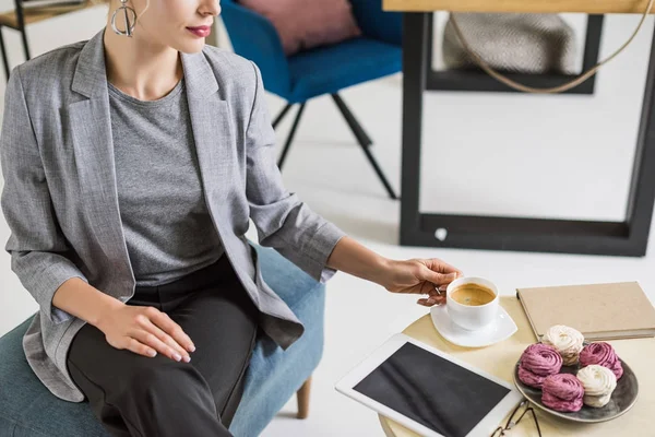 Обрезанный снимок деловой женщины, берущей чашку кофе в офисе — стоковое фото