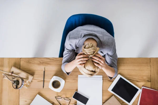 Overhead view of tired businesswoman leaning on workplace in office — Stock Photo