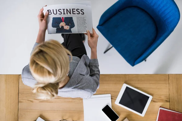 Blick über den Kopf einer Geschäftsfrau, die Zeitung am Arbeitsplatz im Büro liest — Stockfoto