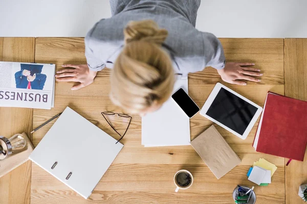 Vue aérienne de la femme d'affaires penchée sur le lieu de travail avec des appareils numériques dans le bureau — Photo de stock