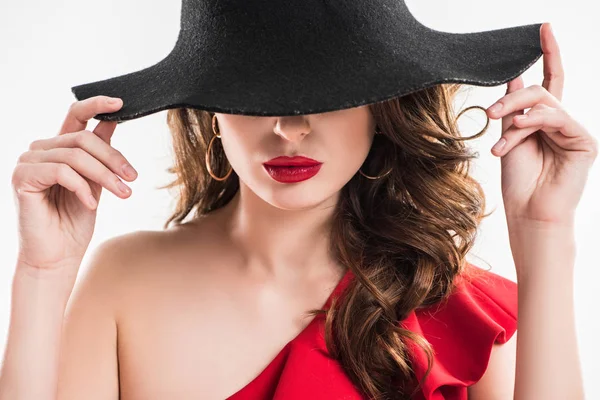 Attractive fashionable girl hiding eyes under black hat isolated on white — Stock Photo