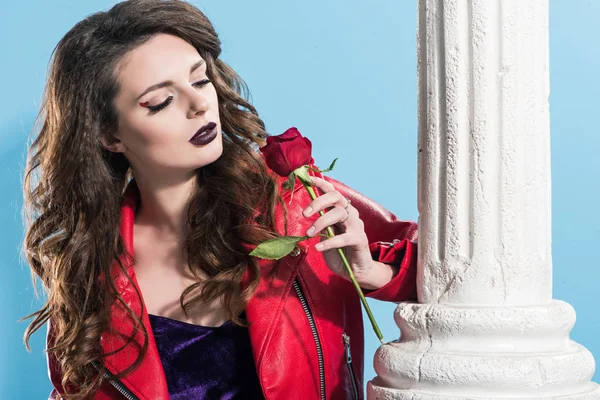 Atractiva chica mirando rojo rosa aislado en azul, San Valentín concepto de día - foto de stock