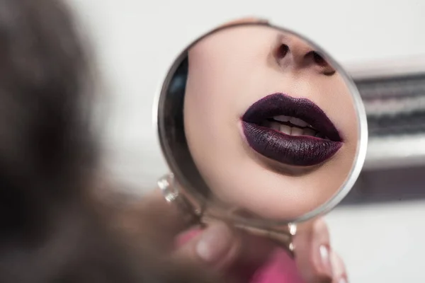Imagen recortada de chica atractiva con los labios oscuros mirando el espejo - foto de stock