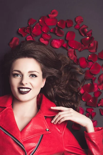 Vista superior de niña sonriente acostada con pétalos de rosas, concepto de día de San Valentín - foto de stock