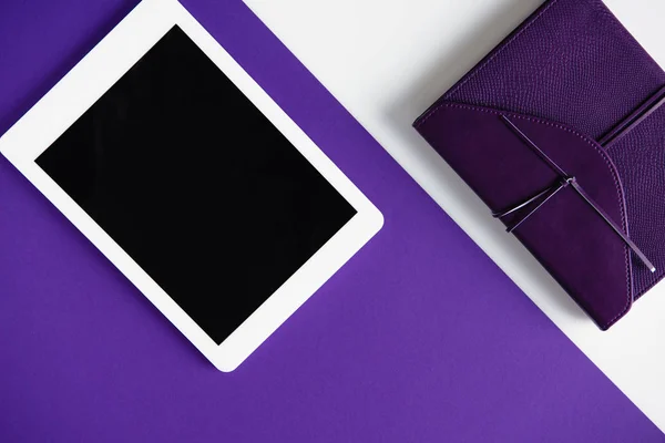 Top view of tablet and notebook on white and purple surface — Stock Photo