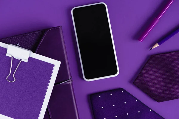 Вид на стильное рабочее пространство в фиолетовых цветовых оттенках со смартфоном и расходными материалами — стоковое фото