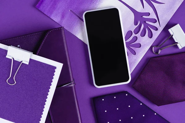 Верхний вид рабочего пространства в фиолетовых оттенках цвета со смартфоном и расходными материалами — стоковое фото