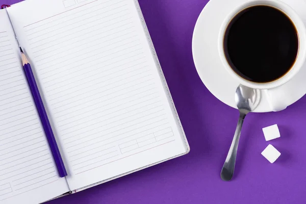 Vista superior del espacio de trabajo con cuaderno en blanco abierto y taza de café - foto de stock