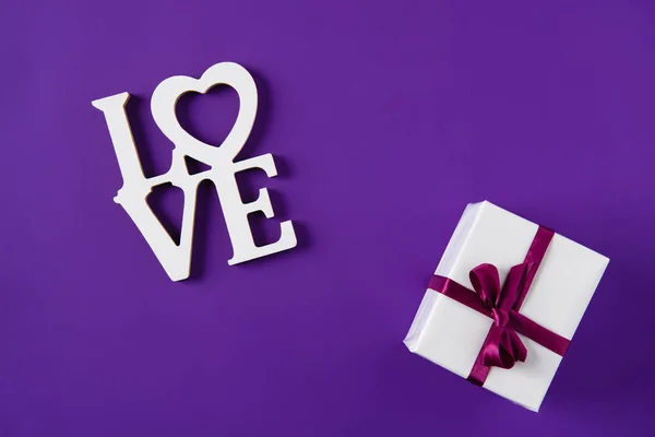 Top view of word love and gift box isolated on purple, valentines day concept — Stock Photo