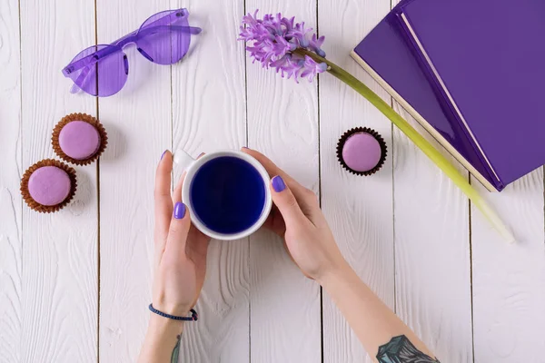 Обрізаний знімок жінки з чашкою фіолетового напою на робочому місці — стокове фото