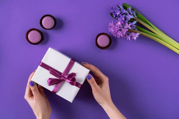 Image recadrée de fille tenant boîte cadeau sur violet — Photo de stock