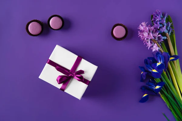 Draufsicht auf Geschenkbox und leckere Macarons auf violett — Stockfoto