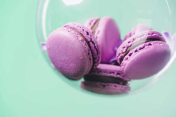 Nahaufnahme von rosa Macarons in Glaskugel auf türkisfarbenem Hintergrund — Stockfoto