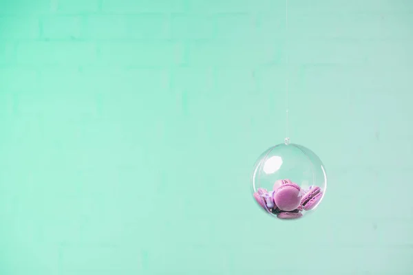 Macarons en bola de cristal colgando sobre fondo azul - foto de stock