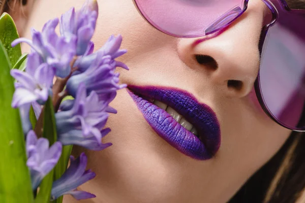 Image recadrée de fille avec des lèvres violettes et des fleurs de jacinthe — Photo de stock