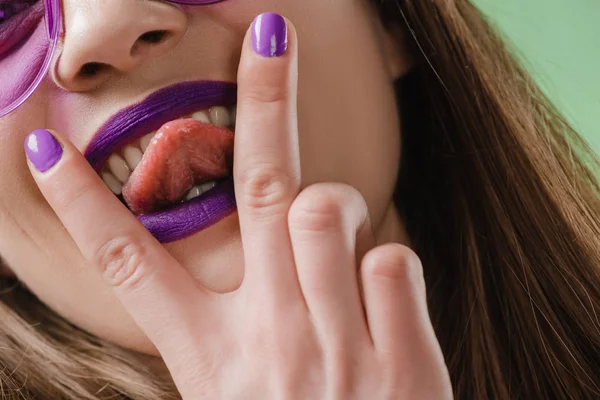 Imagen recortada de chica que saca la lengua entre los dedos - foto de stock