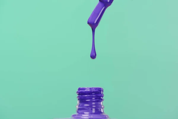 Лак для нігтів вливається в пляшку ізольовано на бірюзовому — Stock Photo