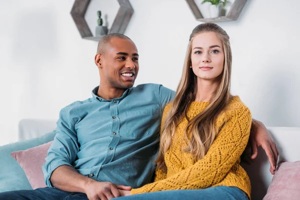 Pareja multicultural cogida de la mano en el sofá - foto de stock