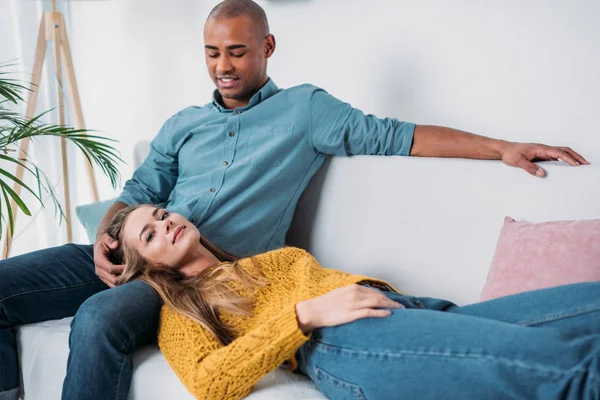 Caucasian girlfriend lying on african american boyfriends legs — Stock Photo