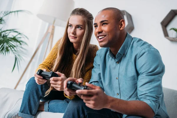 Lächelndes multikulturelles Paar beim Videospiel zu Hause — Stockfoto