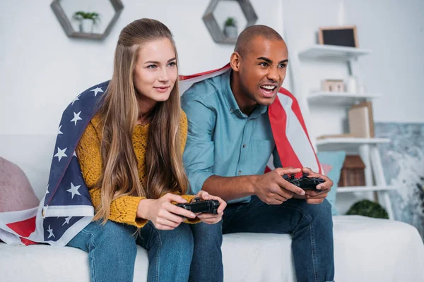 Pareja multicultural jugando videojuego en casa - foto de stock