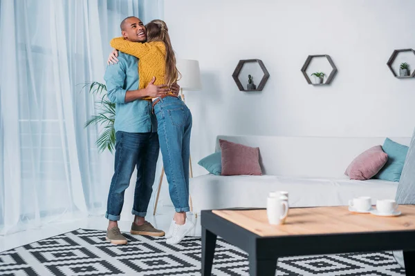 Sorrindo casal multicultural abraçando no quarto — Fotografia de Stock