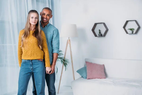 Pareja multicultural tomados de la mano y mirando a la cámara - foto de stock