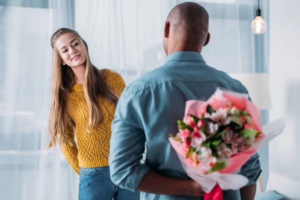 African american boyfriend hiding bouquet behind back — Stock Photo