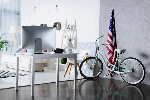 Computador de prata na mesa e bicicleta perto da parede no quarto — Fotografia de Stock