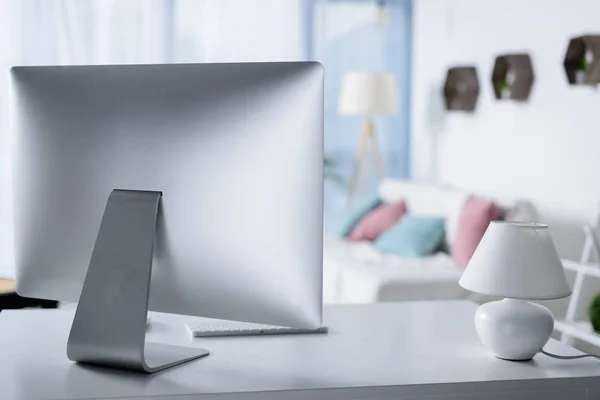 Ordenador de plata en la mesa con lámpara en la habitación - foto de stock