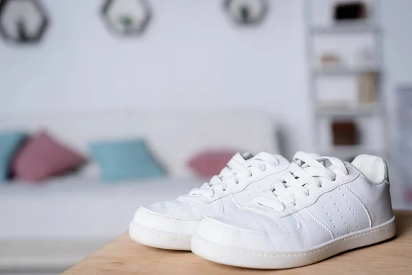 Pair of new white shoes on wooden table in room — Stock Photo