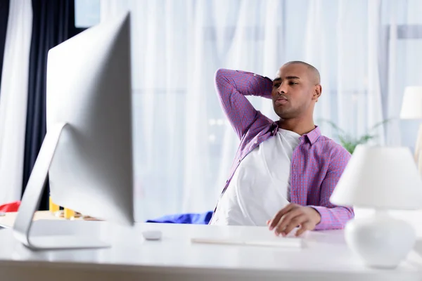 Hombre afroamericano cansado mirando el ordenador en casa - foto de stock