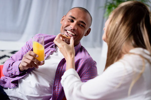 Caucasian girlfriend feeding african american boyfriend — Stock Photo