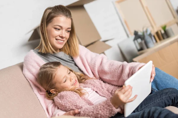 Feliz madre e hija usando tableta digital durante la reubicación - foto de stock