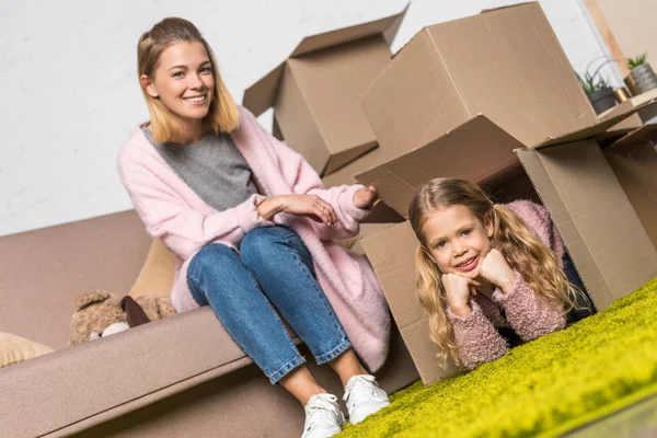 Mãe feliz e filha se divertindo com caixas de papelão ao se mudar — Fotografia de Stock
