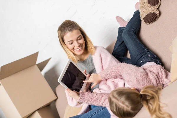 Mère heureuse et fille en utilisant une tablette numérique avec écran vide tout en déménageant à la maison — Photo de stock