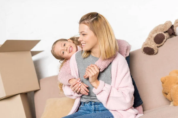 Glückliche Mutter und Tochter umarmen sich während des Umzugs auf dem Sofa — Stockfoto