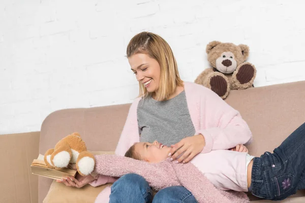 Mãe feliz e filha se divertindo juntos no sofá — Fotografia de Stock