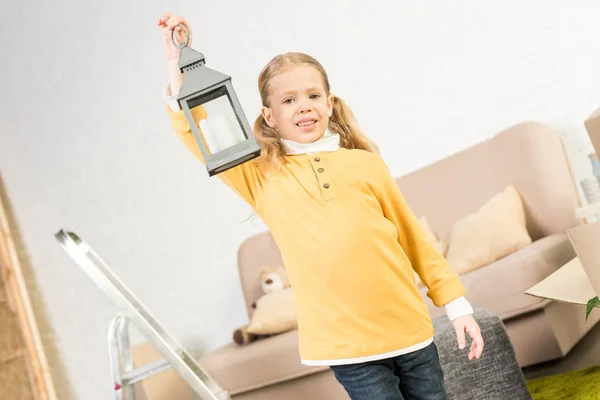 Happy little child holding lantern and smiling at camera while moving home — Stock Photo