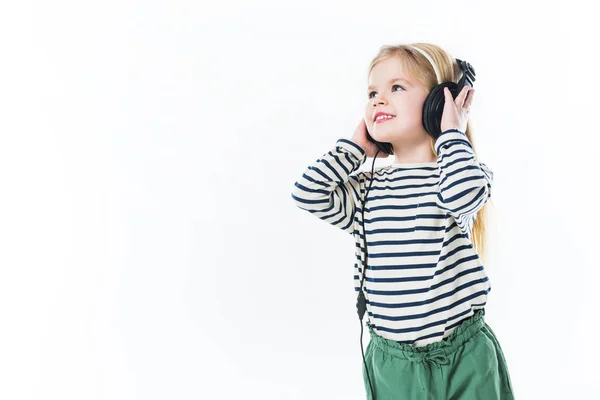 Счастливый маленький ребенок слушает музыку с наушниками изолированы на белом — стоковое фото