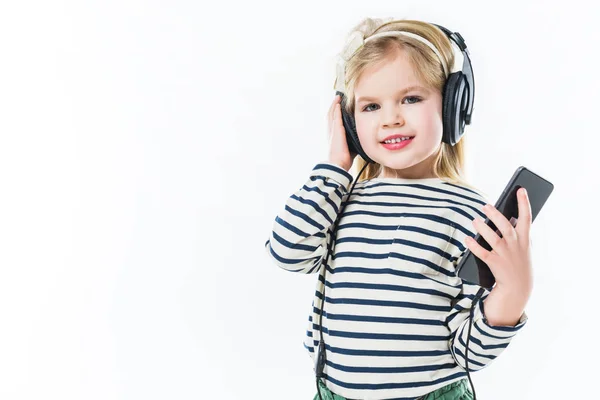 Adorable little child listening music with headphones and smartphone isolated on white — Stock Photo