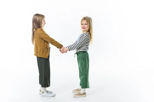 Entzückende kleine Schwestern, die die Hände isoliert auf weiß halten — Stockfoto