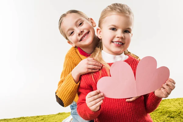 Hermanitas con corazón de cartón rosa para tarjeta de felicitación hecha a mano aislada en blanco - foto de stock