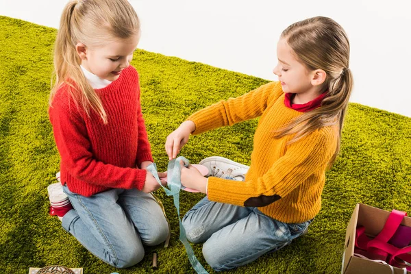 Niñas haciendo tarjeta de felicitación hecha a mano mientras están sentadas en el suelo aisladas en blanco - foto de stock