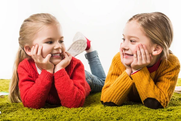 Adorabili sorelline isolate distese sul tappeto verde isolate sul bianco — Foto stock