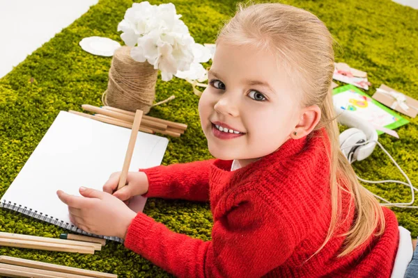 Beautiful little child drawing with color pencils on green soft carpet — Stock Photo